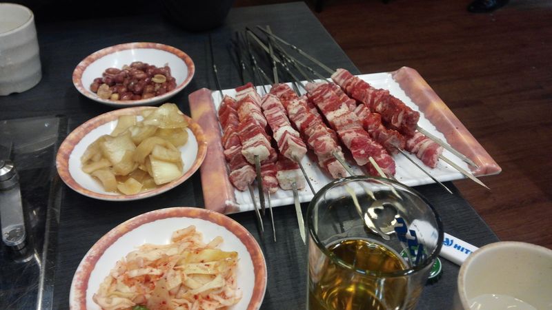 Photo de brochettes d'agneau accompagné d'assiettes d'assortiments et d'une boisson