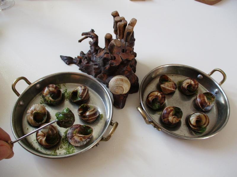 Photo de deux demi-douzaines d'escargots en sauce au beurre persillé, cuits.