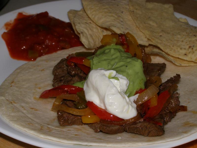 Photo d'une assiette de fajitas, avec des légumes et de la sauce.