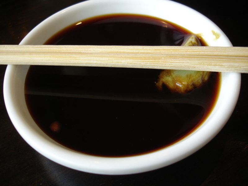 Photo d'un bol d'huile de soja accompagné de ses baguettes asiatiques