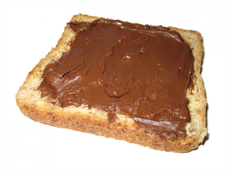 Photo dune tranche de pain recouverte de pâte à tartiner chocolat et noisette.