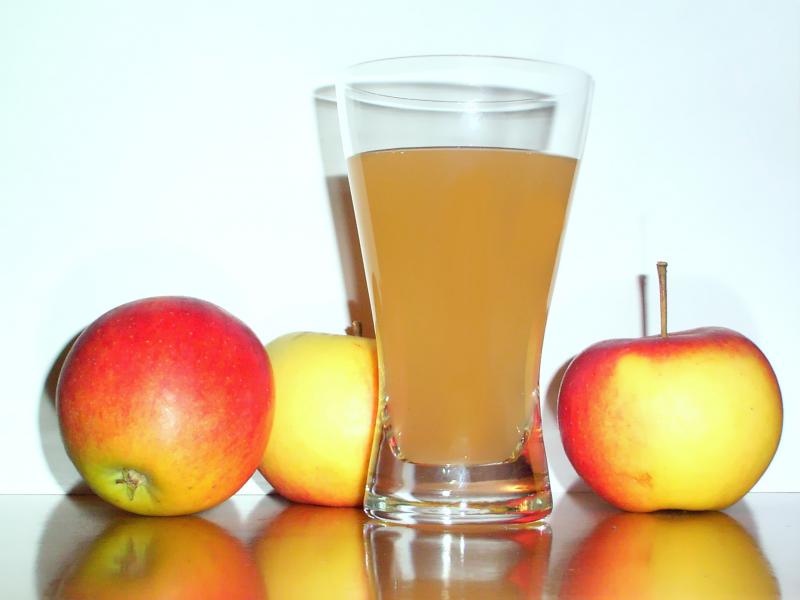 Photo d'un verre de jus de pomme, pur jus et de 3 pommes.
