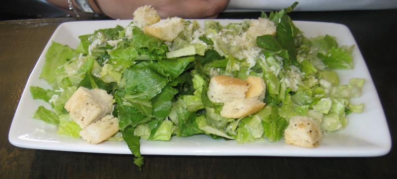 Photo d'une assiette de salade César au poulet (salade verte, fromage, croûtons, sauce).