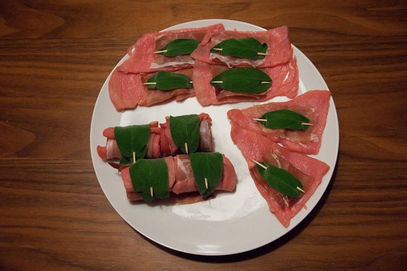 Photo d'une assiette d'escalopes de veau crue, parfumée avec des feuilles de sauge.