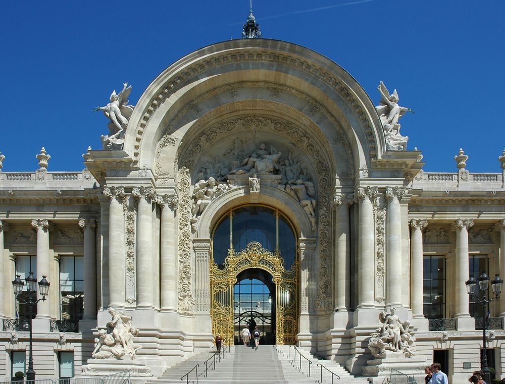 Une grille en fer doré et des statues ainsi que des colonnes blanches accueillent les visiteurs de ce Musée.