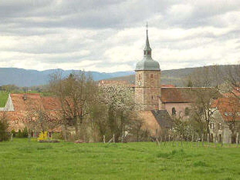 Village de Buc,avec église et herbe verte printanière, dans le département du Territoire de Belfort.