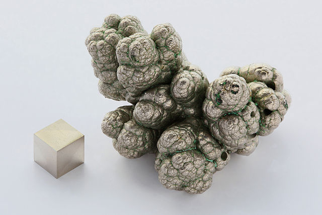 Nodule de nickel pure à 99,9%, raffinés par électrolyse, à coté d'un cube d'1 cm³ de nickel de pureté (99,99 % = 4N), pour comparaison.