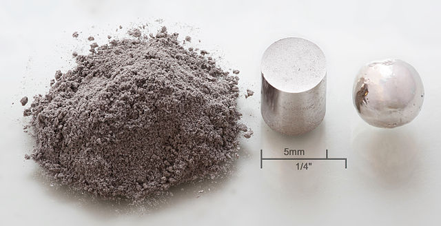 Trois formes de l'élément Rhodium: 1 g sous forme de poudre, un cylindre de 1 g obtenu par compression, une pastille refondue de 1 g obtenue sous atmospère inerte à l'aide d'un arc électrique.