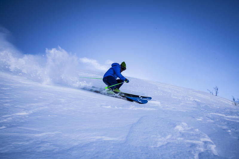 Un homme glisse sur une piste de ski en s'aidant de ses bâtons
